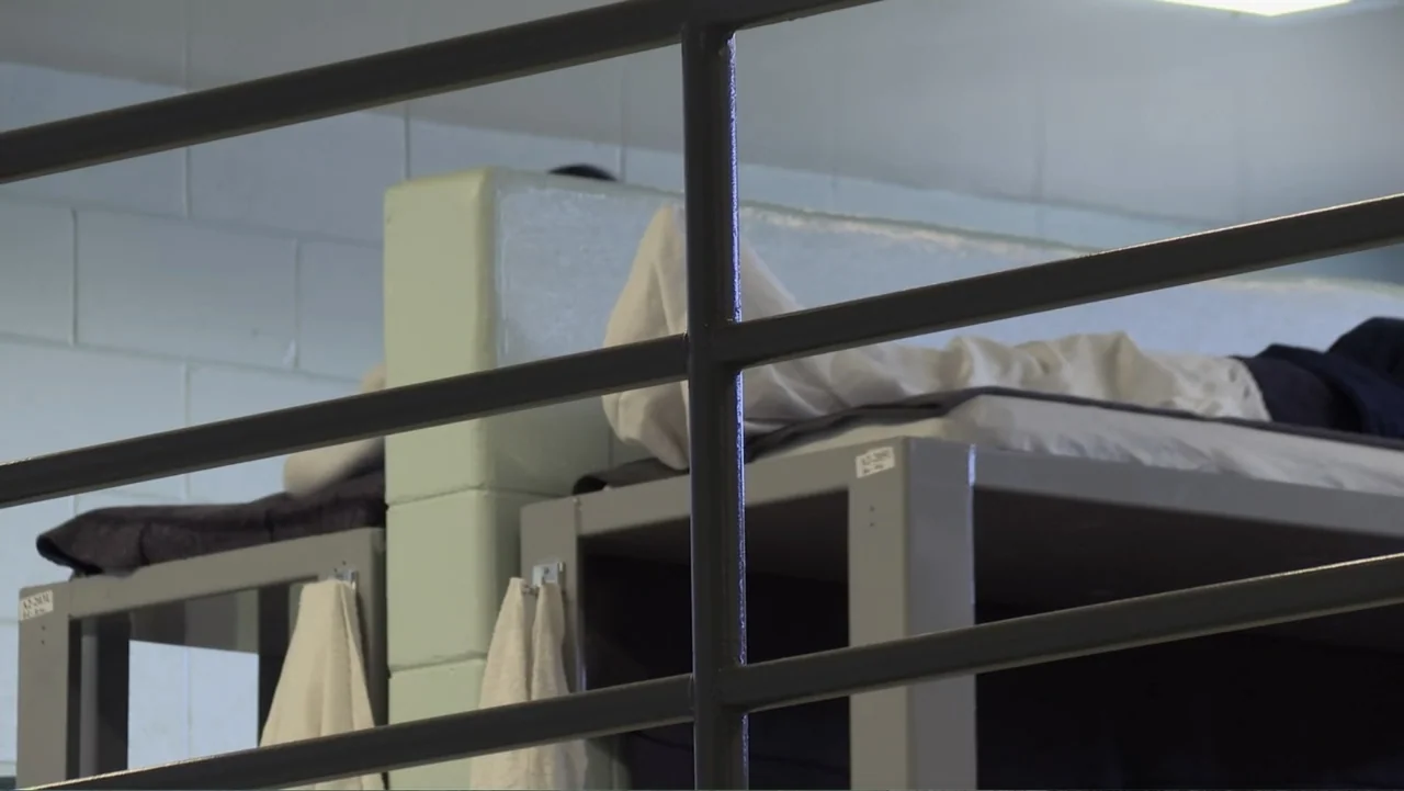 Torn Apart: Separated at the Border (2019) movie still: medium — A stark institutional room features tiered metal bunks against a light-colored…