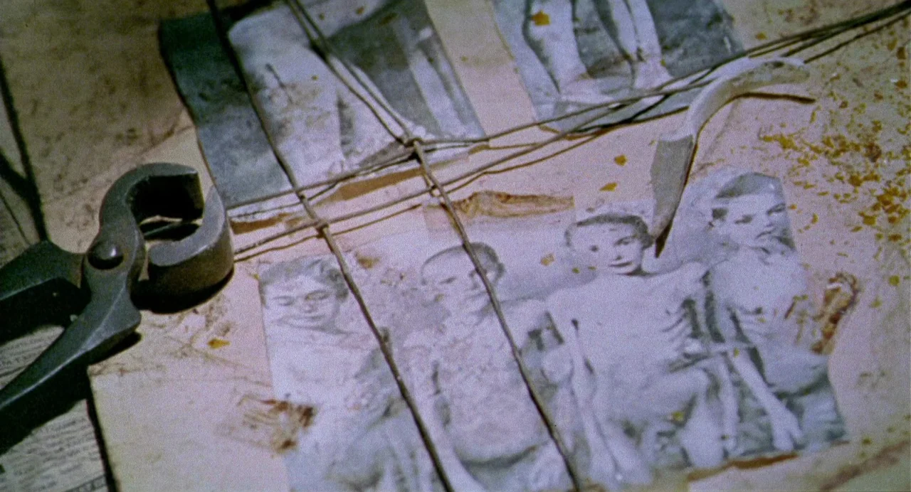 The Nameless (1999) movie still: closeup — A cluttered, stained wooden surface displays a collection of old, black-and-white photographs. Several…