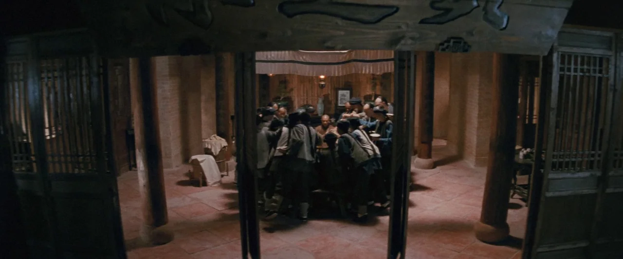 Once Upon a Time in China (1991) movie still: wide — A spacious room with wooden pillars and tiled flooring features a communal gathering. A small…