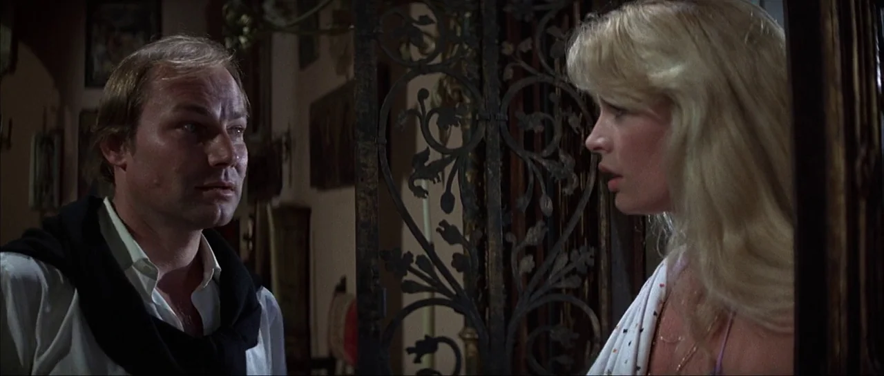 Never Say Never Again (1983) movie still: medium — A dimly lit indoor space features an intricate black wrought iron gate partition. A man and a…