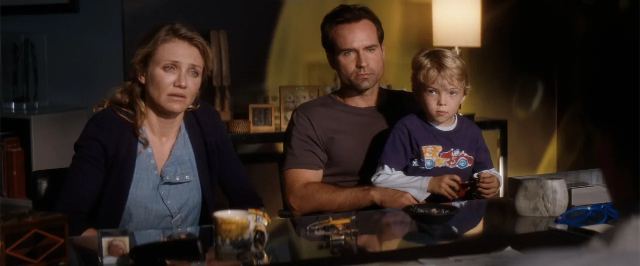 My Sister's Keeper (2023) movie still: medium — A dimly lit home office features a glass desk and shelving filled with various objects. A woman, a…