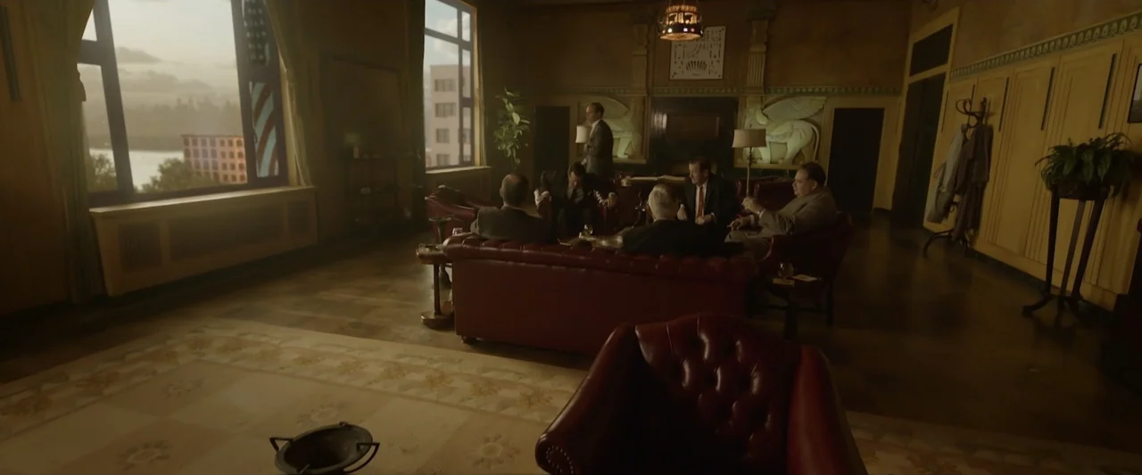 Reagan (2024) movie still: wide — An opulent 1940s club room features leather furniture and ornate plaster reliefs on walls. Five men in suits…