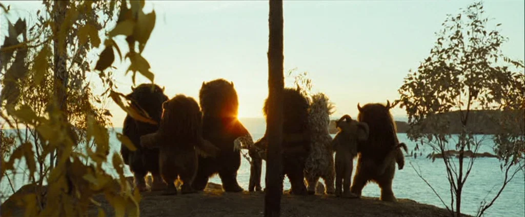 Where The Wild Things Are (2009) movie still: wide — A group of six diverse monster creatures stands on a coastal cliff at sunset. They look toward…