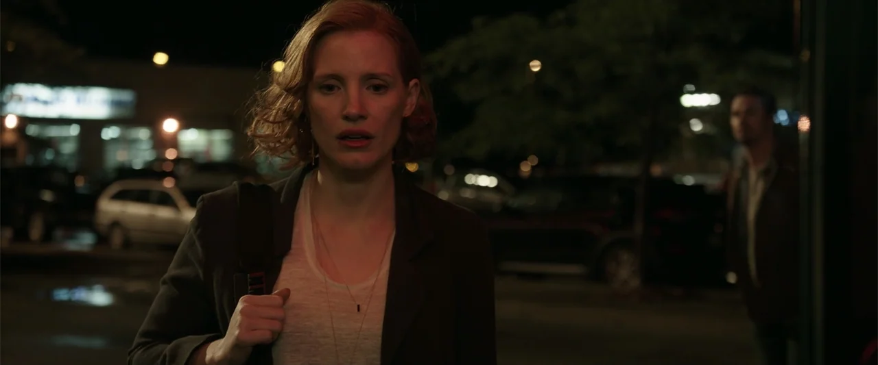 K.G.F: Chapter 2 (2022) movie still: medium — An outdoor parking lot at night with blurred vehicles and trees in the background. A woman in a dark…