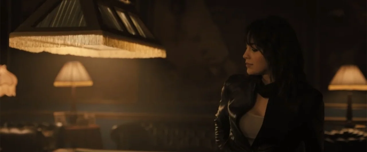 Abigail (2024) movie still: medium — A dimly lit billiard hall features multiple lamps casting pools of soft warm light. A woman in a black leather…