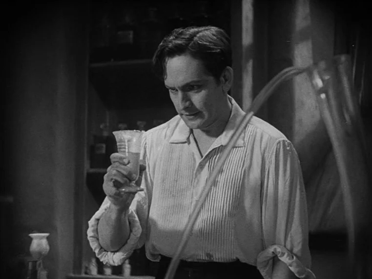 Dr. Jekyll and Mr. Hyde (1931) movie still: medium — A dark laboratory filled with shelves of glass bottles and scientific equipment. A man in a…
