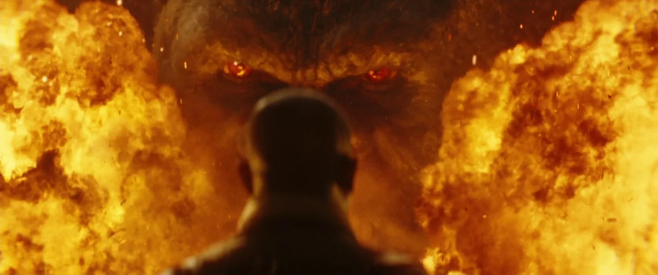 Kong: Skull Island (2017) movie still: medium — A wall of intense flames erupts in an outdoor environment at night. A man stands in the foreground…