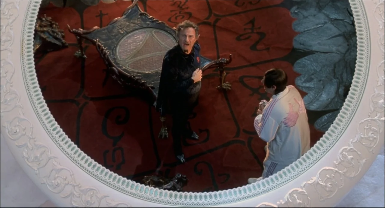 Little Nicky (2000) movie still: wide — A spacious room features a large circular table frame surrounding a red patterned floor. A man in a dark…
