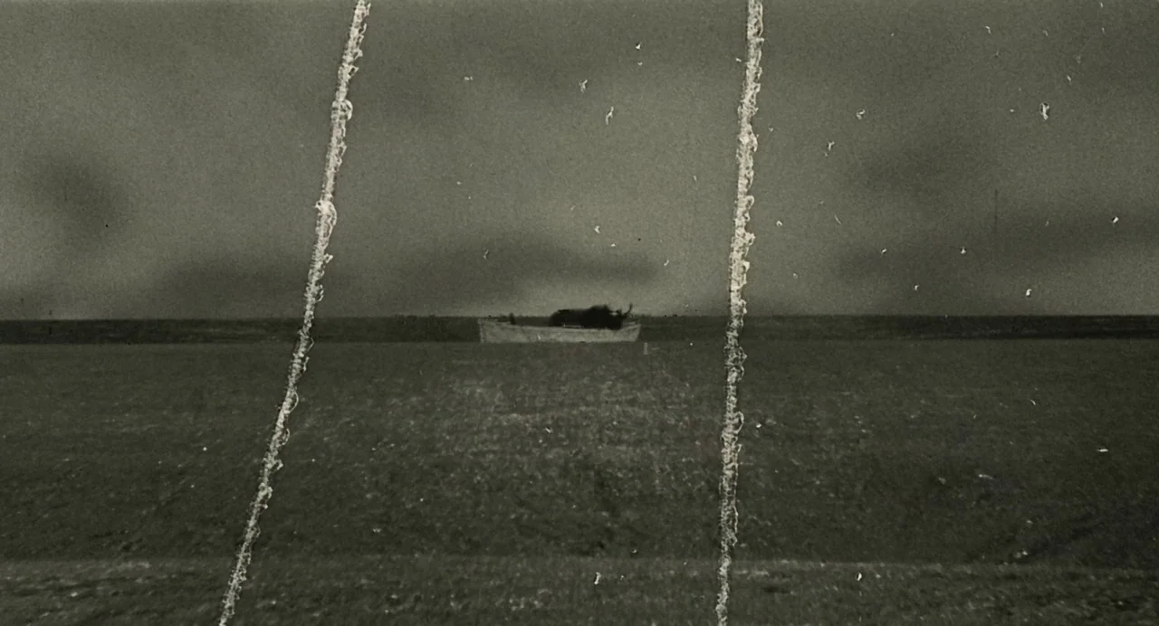 And The Ship Sails On (1983) movie still: wide — A dark, empty body of water stretches across the frame under a cloudy sky. A small, distant boat…