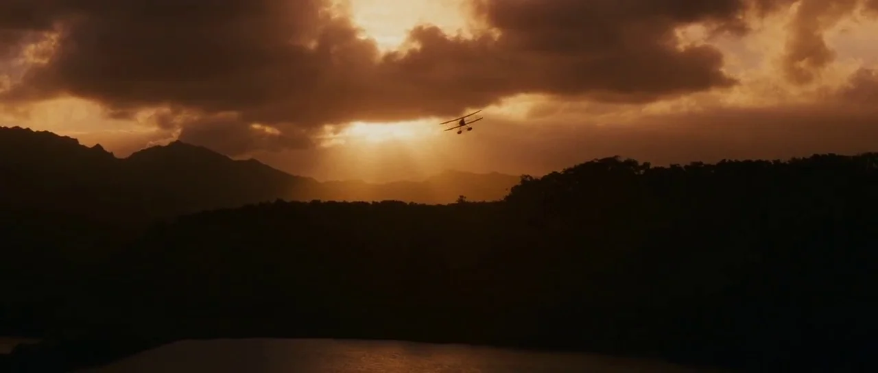 Raiders Of The Lost Ark (1981) movie still: wide — A dark mountainous silhouette stretches beneath a bright golden-hued sunset sky. A single small…