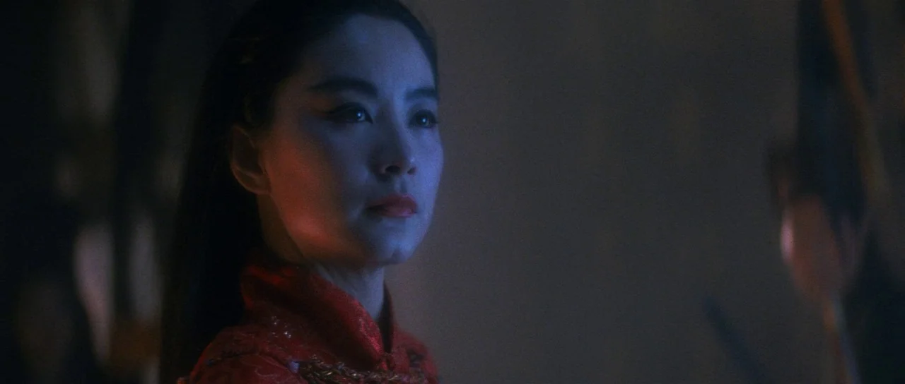 The Bride With White Hair (1993) movie still: closeup — A dimly lit interior space with a subject positioned in the frame center. A woman with long…