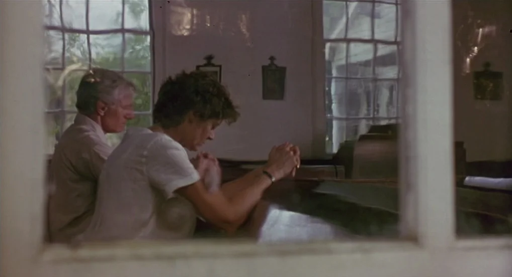 Dead Man Walking (1995) movie still: medium — A wooden church interior with large multi-paned windows and simple wall-mounted crosses. An older man…