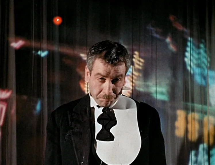 Zazie Dans Le Métro (1960) movie still: medium — A man in formal evening wear stands in front of a translucent projection screen. Colorful abstract…