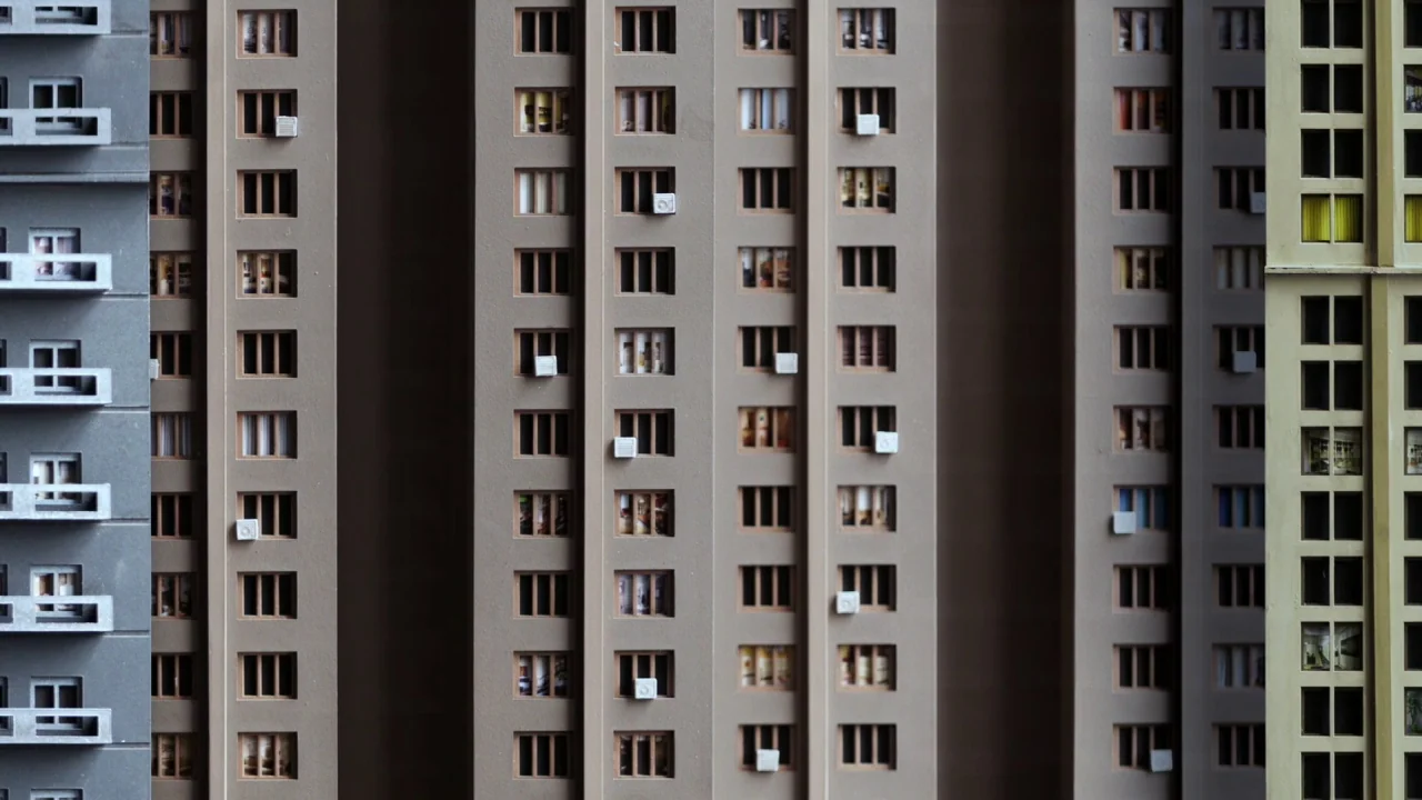 Piercing (2018) movie still: wide — A dense arrangement of architectural apartment building models fills the entire field of view. Multiple window…