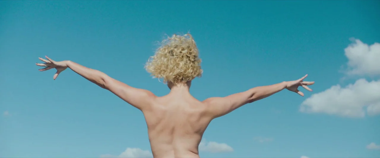 Godzilla x Kong: The New Empire (2024) movie still: medium — An open blue sky with small white clouds fills the frame entirely. A woman with blonde…