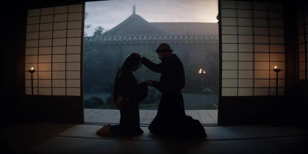 Shogun (2024) movie still: fullbody — A traditional Japanese room features shoji screens framing an open view of a garden. A man kneels on the floor…