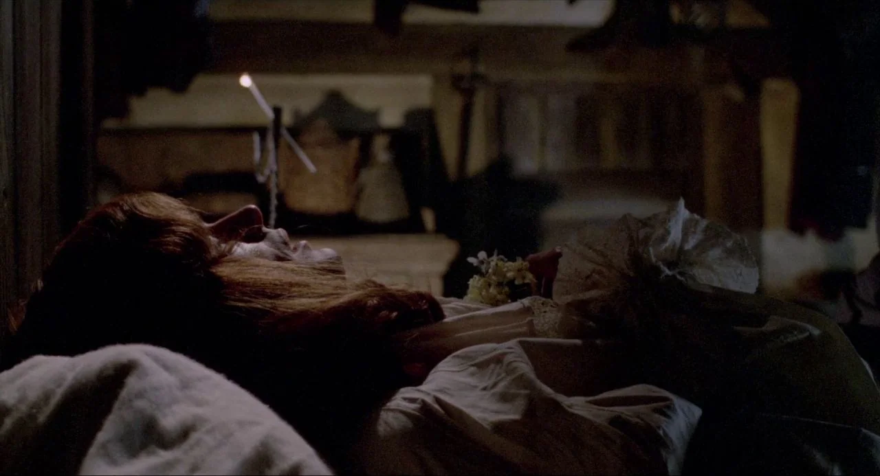 The Blood on Satan’s Claw (1971) movie still: closeup — A dim, dark room is filled with shadow and a singular burning candle. A woman with auburn…