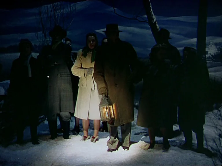 Black Narcissus (1947) movie still: fullbody — A group of individuals in winter coats gathers on a snowy expanse at night. A man in the center holds…