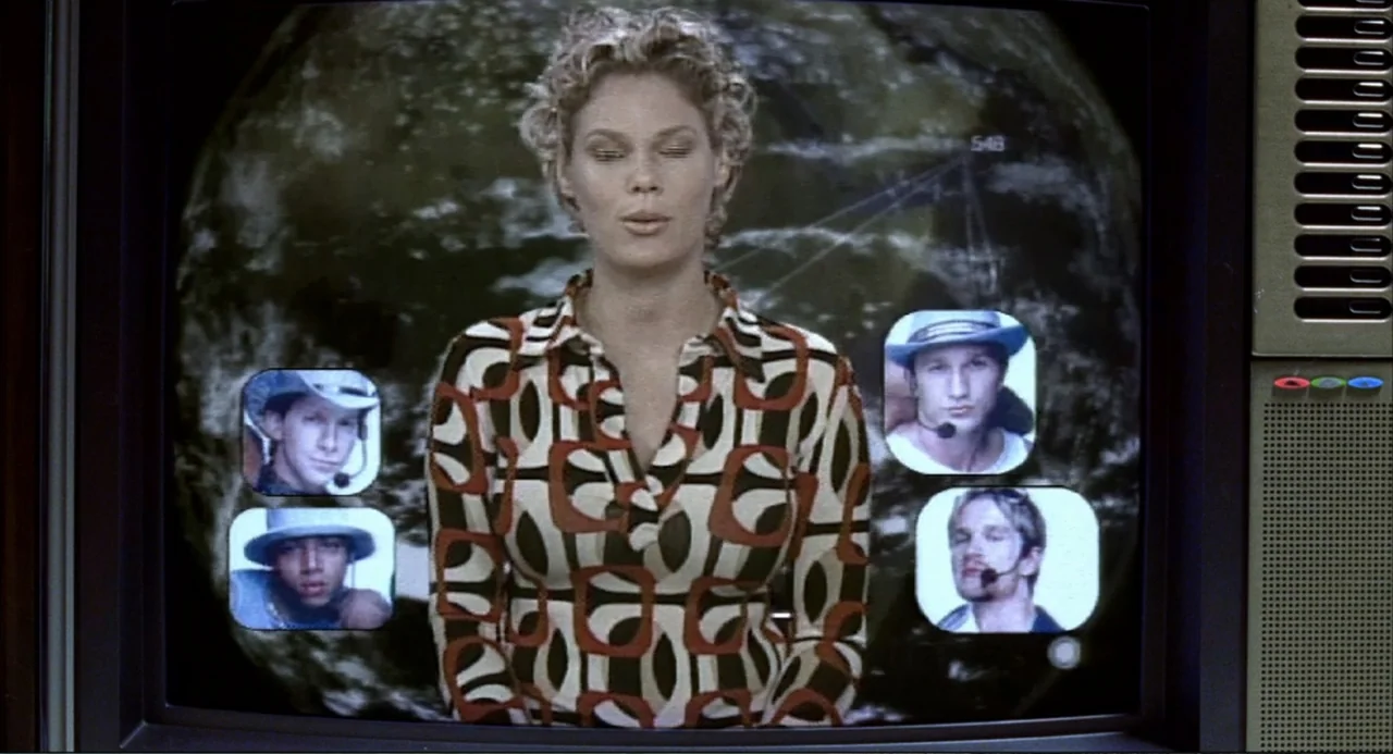Josie and the Pussycats (2001) movie still: medium — A close-up view of a television screen showing a news anchor presenting content. The woman…