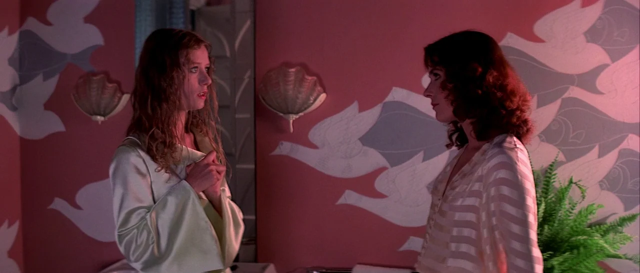 Suspiria (1977) movie still: medium — A bathroom features walls covered in patterned wallpaper with stylized bird and fish illustrations. Two women…
