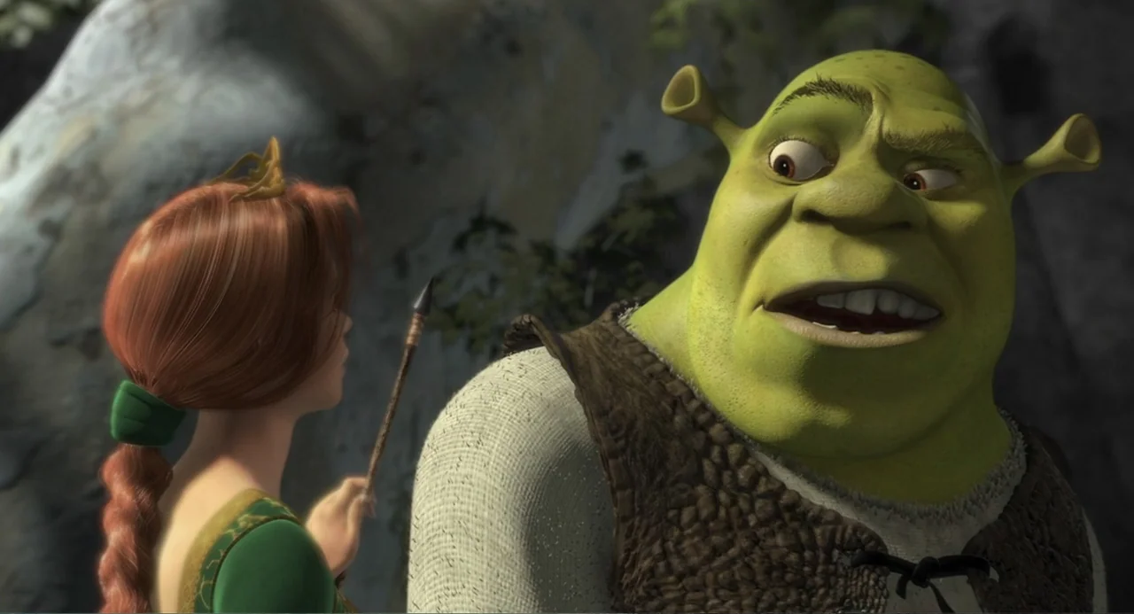 Shrek (2001) movie still: medium — A rocky, cavernous exterior provides the backdrop for two fantasy characters. A green ogre in a brown vest…