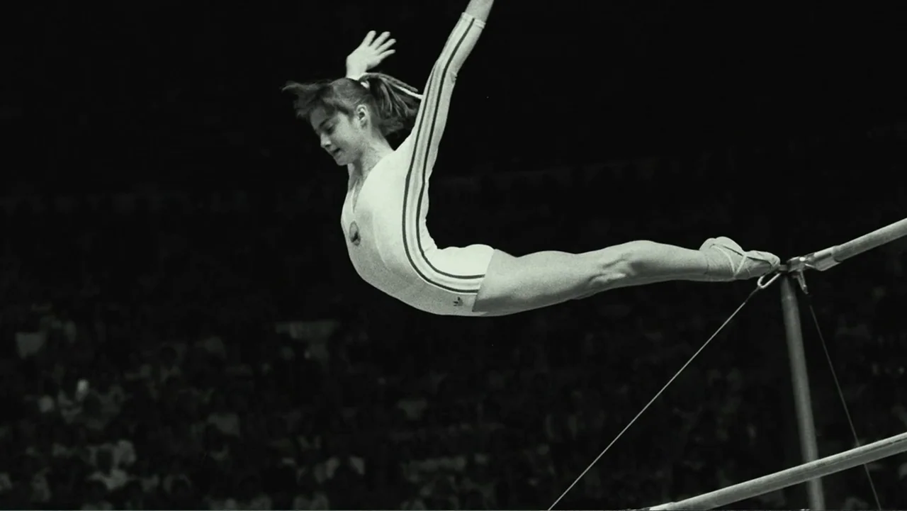 At the Heart of Gold: Inside the USA Gymnastics Scandal (2019) movie still: fullbody — A dark arena at night features a female gymnast performing on…