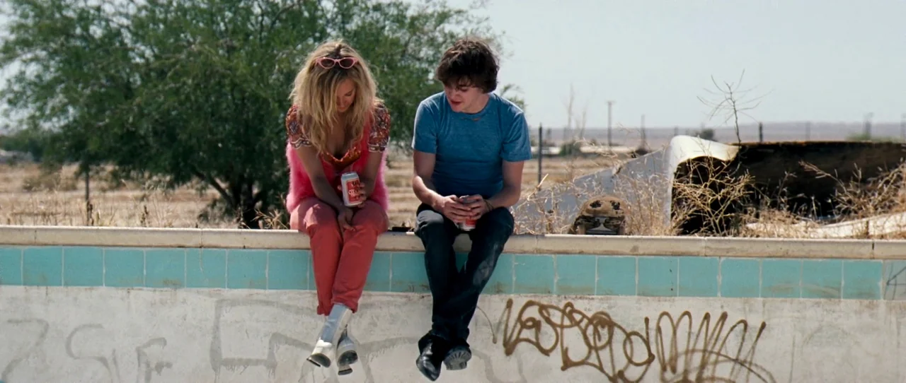 Little Birds (2011) movie still: medium — A dry, graffiti-covered swimming pool in a suburban, sun-bleached desert setting. A young man and woman…