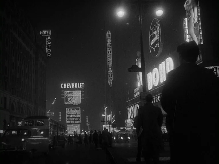 Killer’s Kiss (1955) movie still: wide — A dense urban night scene filled with towering, glowing advertisement signage in Times Square. Several…
