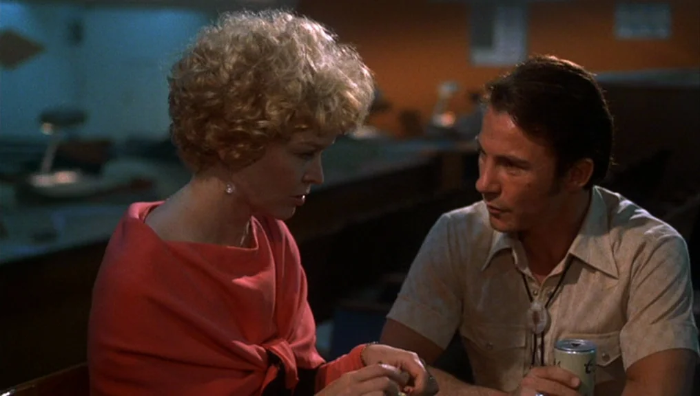 Alice Doesn’t Live Here Anymore (1974) movie still: medium — Two individuals sit in a dark diner booth during the evening hours. They are positioned…