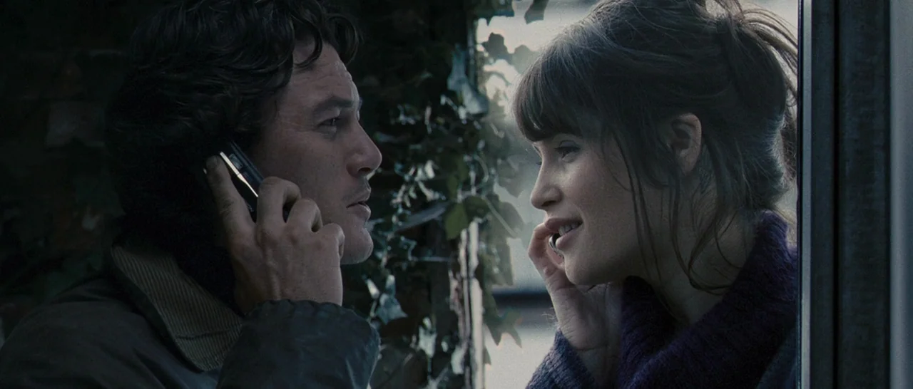 Tamara Drewe (2010) movie still: medium — A man and woman stand on opposite sides of a window frame surrounded by ivy. Both individuals are talking…