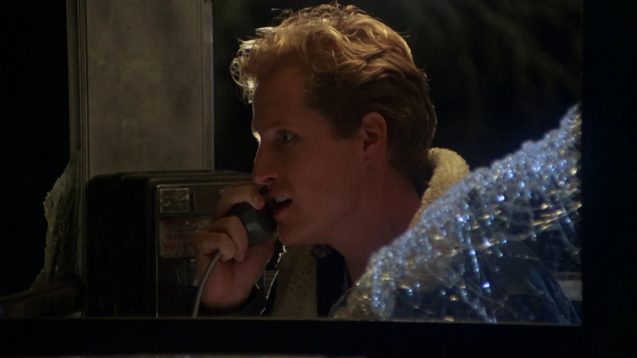 Friday the 13th Part VI: Jason Lives (1986) movie still: closeup — A man speaks into a public telephone inside a dark, nighttime booth. The frame is…