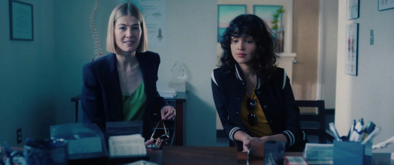 I Care A Lot (2020) movie still: medium — A medical professional's workspace with anatomical wall charts and anatomical spinal models present. Two…