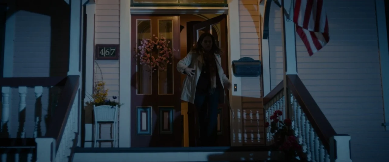 God Bless the Broken Road (2018) movie still: medium — A residential house porch at night features a dark door and white siding. A woman in a tan…