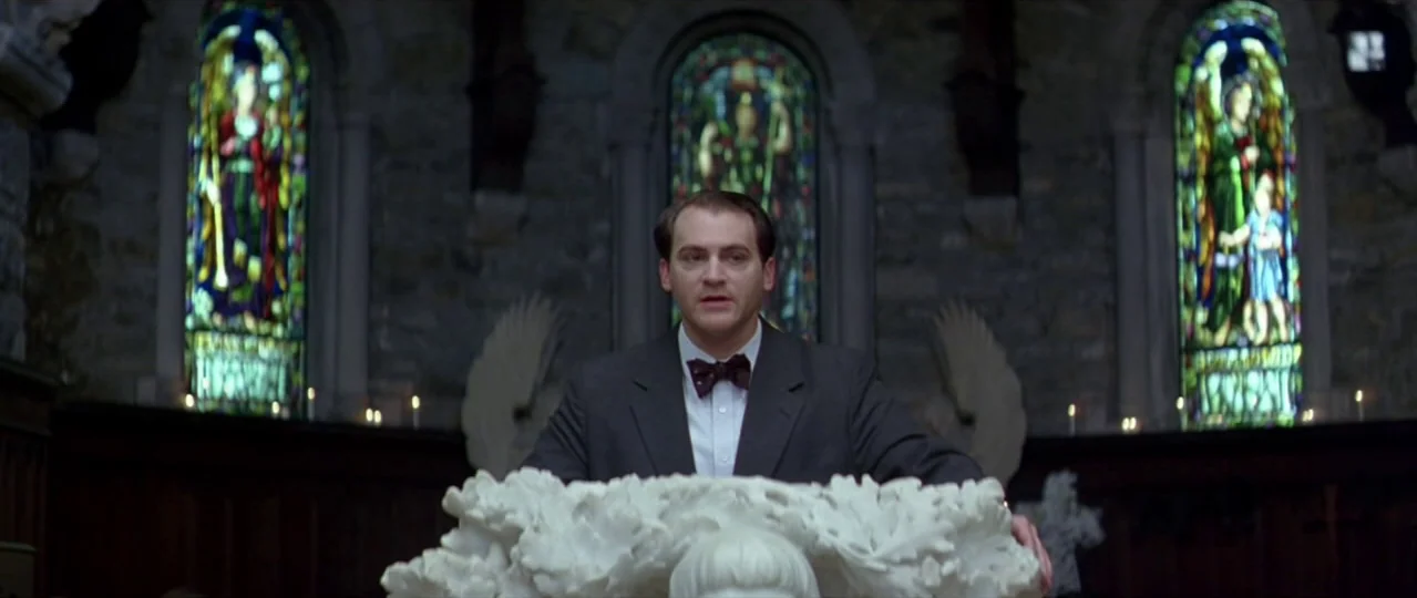 Afterschool (2008) movie still: medium — A stone church interior features three arched stained glass windows behind a white altar. A man in a dark…