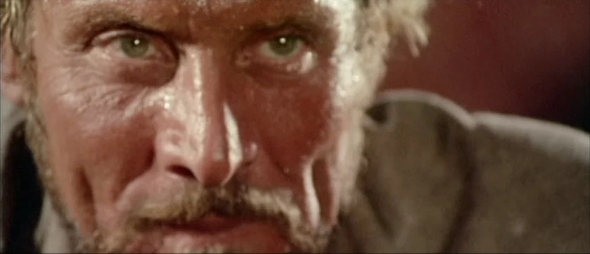Django Kill (1967) movie still: closeup — An arid desert setting under bright sunlight with a close view of a man. The man stares directly into the…