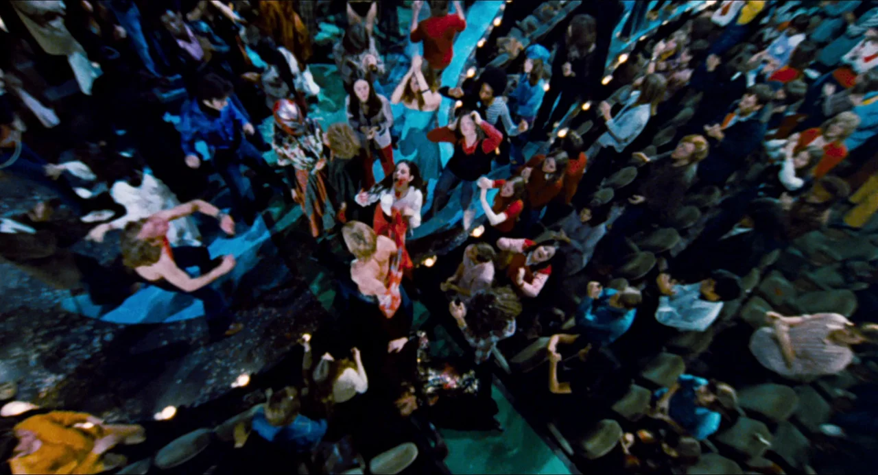 Phantom of the Paradise (1974) movie still: wide — A crowded auditorium floor is illuminated by harsh lights during an active event. Numerous…