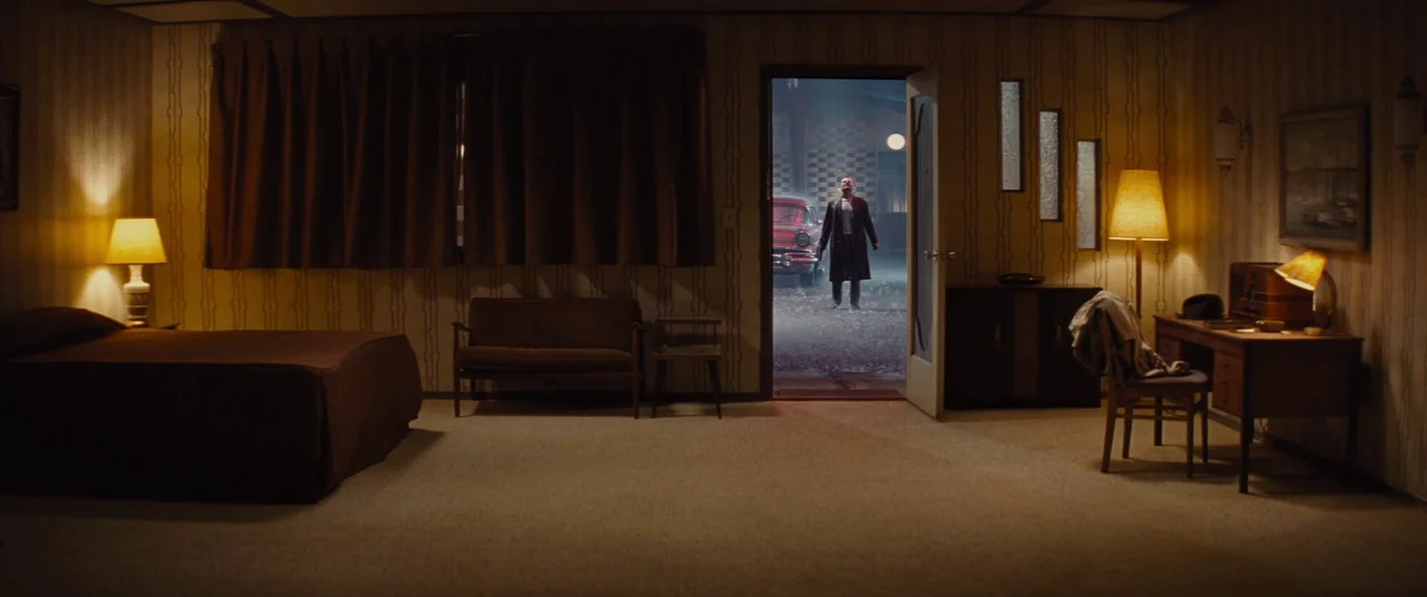 Bad Times at the El Royale (2018) movie still: wide — A dimly lit room with vintage 1950s wallpaper features a bed and a writing desk. A man stands…