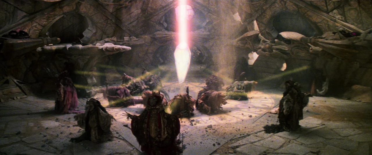 The Dark Crystal (1982) movie still: wide — A dark, vaulted stone chamber features intricate carvings on the walls and floors. Multiple hooded…