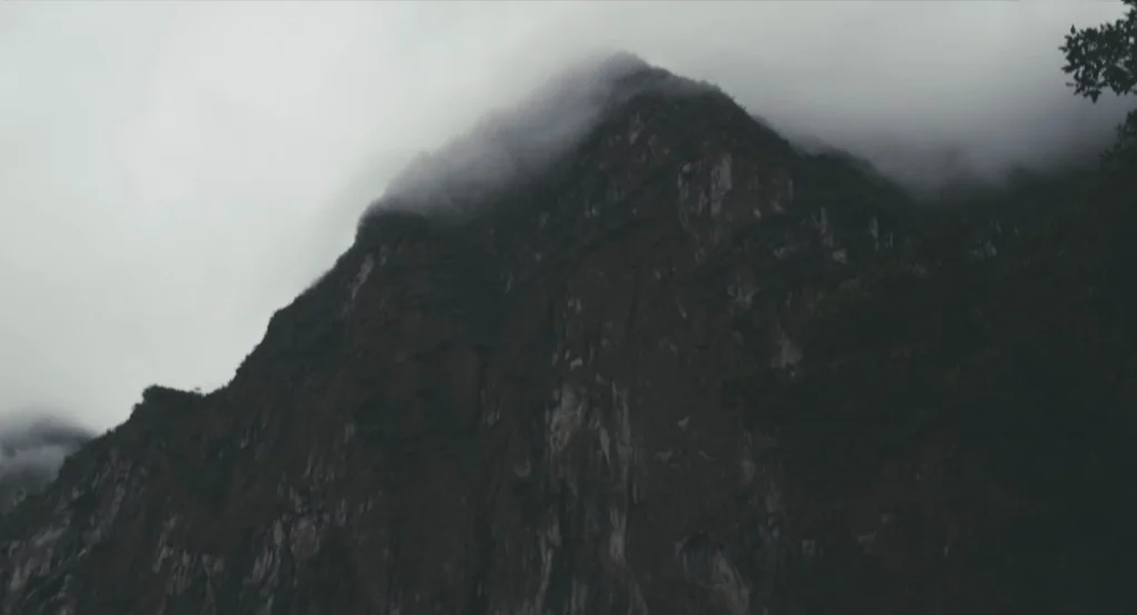 My Son, My Son, What Have Ye Done? (2009) movie still: establishing — A dark, craggy mountain peak rises into thick white clouds and heavy fog. The…