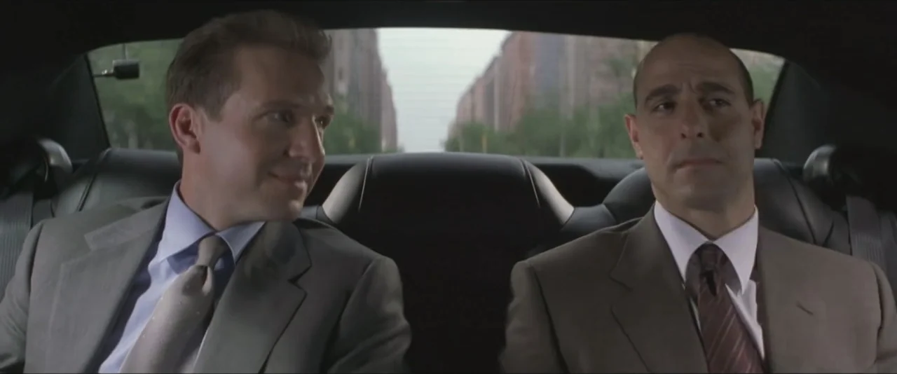 Maid in Manhattan (2002) movie still: medium — Two men sit in the backseat of a moving car during the day. They are wearing business attire and…