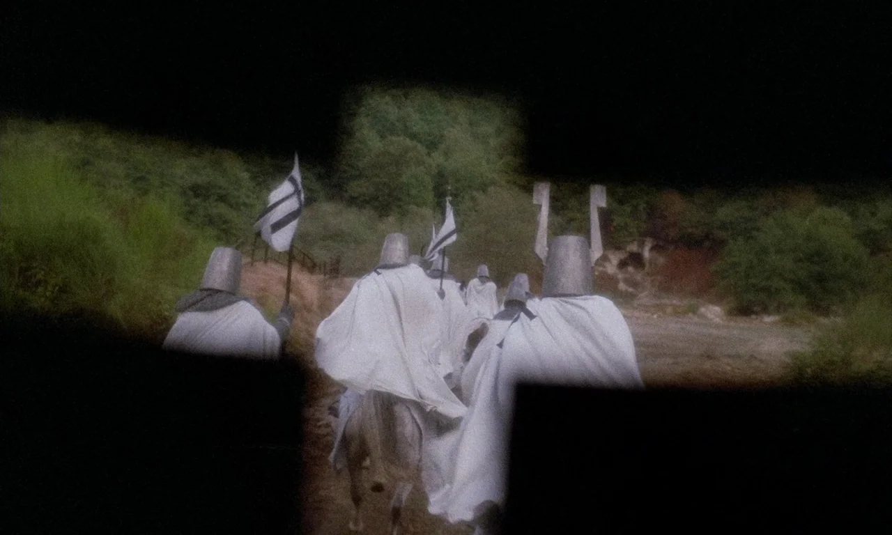 The Church (1989) movie still: wide — Several riders in white cloaks and metal helmets travel along a narrow dirt path. The figures move away from…