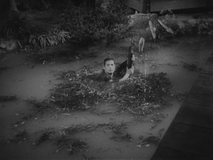 Sanshiro Sugata (1943) movie still: wide — A murky, weed-filled pool of water sits in a dark, outdoor woodland environment. A man in dark clothing…