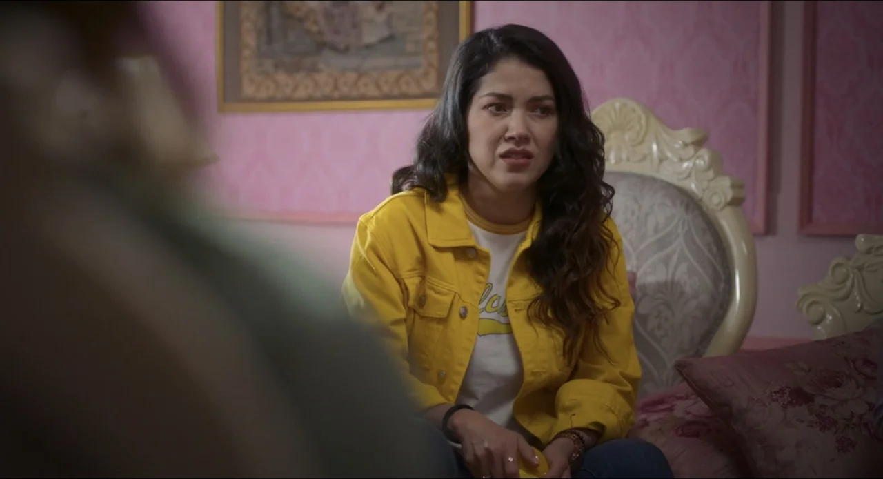 The Beauty and the Moody (2022) movie still: medium — A bedroom features pink wallpaper with ornate wall art and a large upholstered headboard. A…