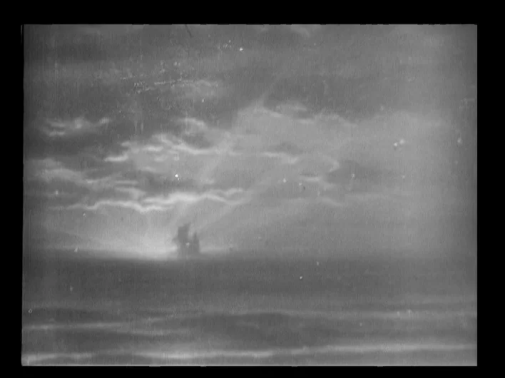 The Man Who Laughs (1928) movie still: establishing — A dark, silhouetted ship appears on the horizon of a vast, turbulent ocean. Clouds stretch…