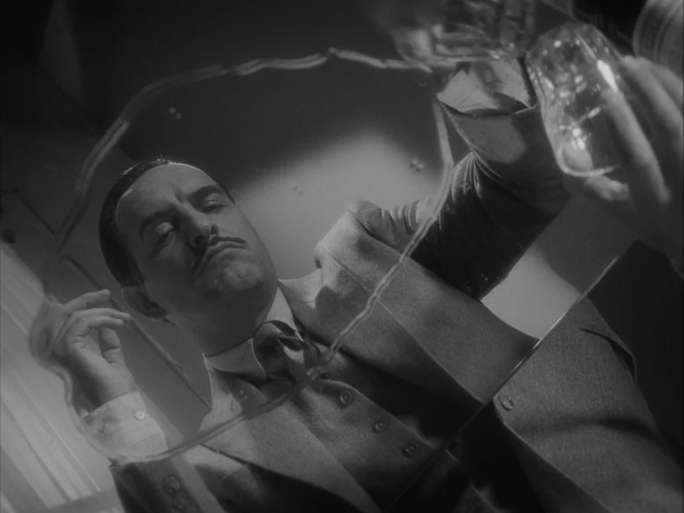 The Artist (2011) movie still: closeup — The perspective is from beneath a glass surface, showing a man's reflection looking down. The man is…