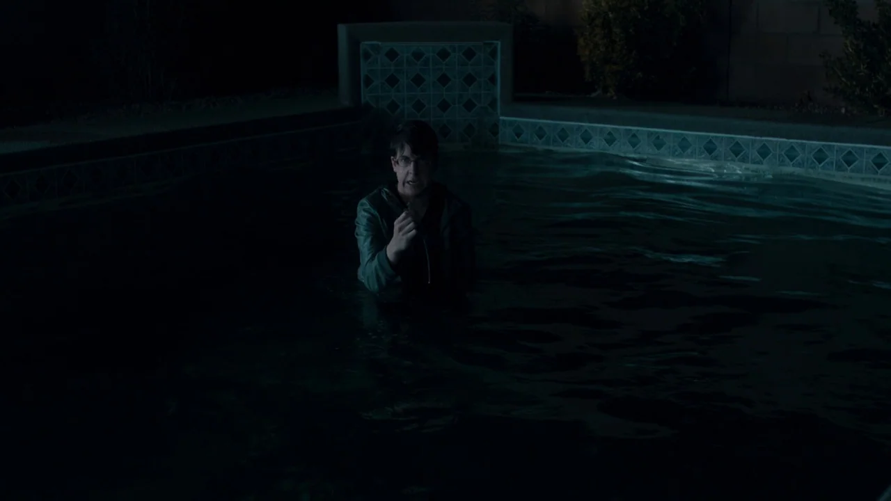 Fright Night (2011) movie still: medium — A man stands in a dark, empty swimming pool at night. He is submerged to his chest while holding a small…