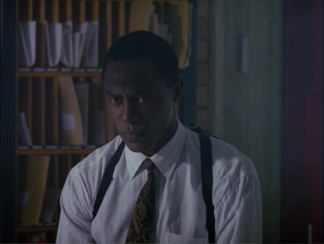 Code Name: Wolverine (1996) movie still: medium — An indoor office space features wooden mail cubbies filled with folders in the background. A man…