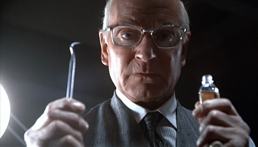 Marathon Man (1976) movie still: closeup — A dimly lit room with an elderly man looming directly over the camera lens. He holds a sharp dental pick…