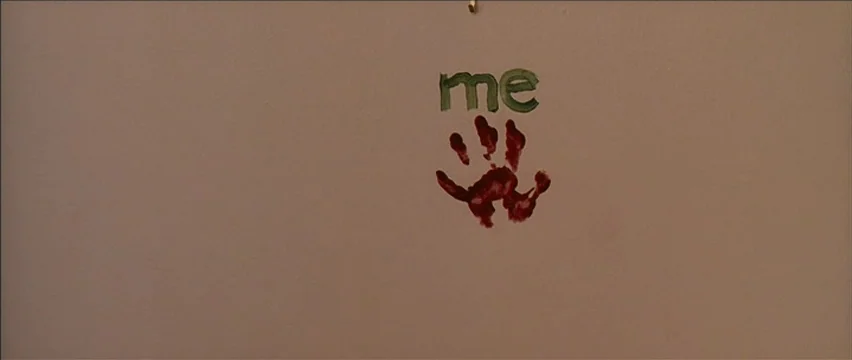 Snow Angels (2007) movie still: closeup — A plain, light-colored interior wall serves as the background for painted elements. A red handprint is…