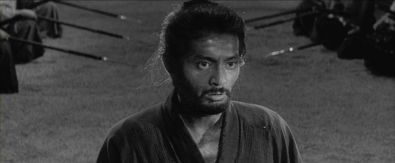 Harakiri (1962) movie still: medium — An open field at daytime serves as the backdrop for a tense gathering. A bearded man in traditional clothing…